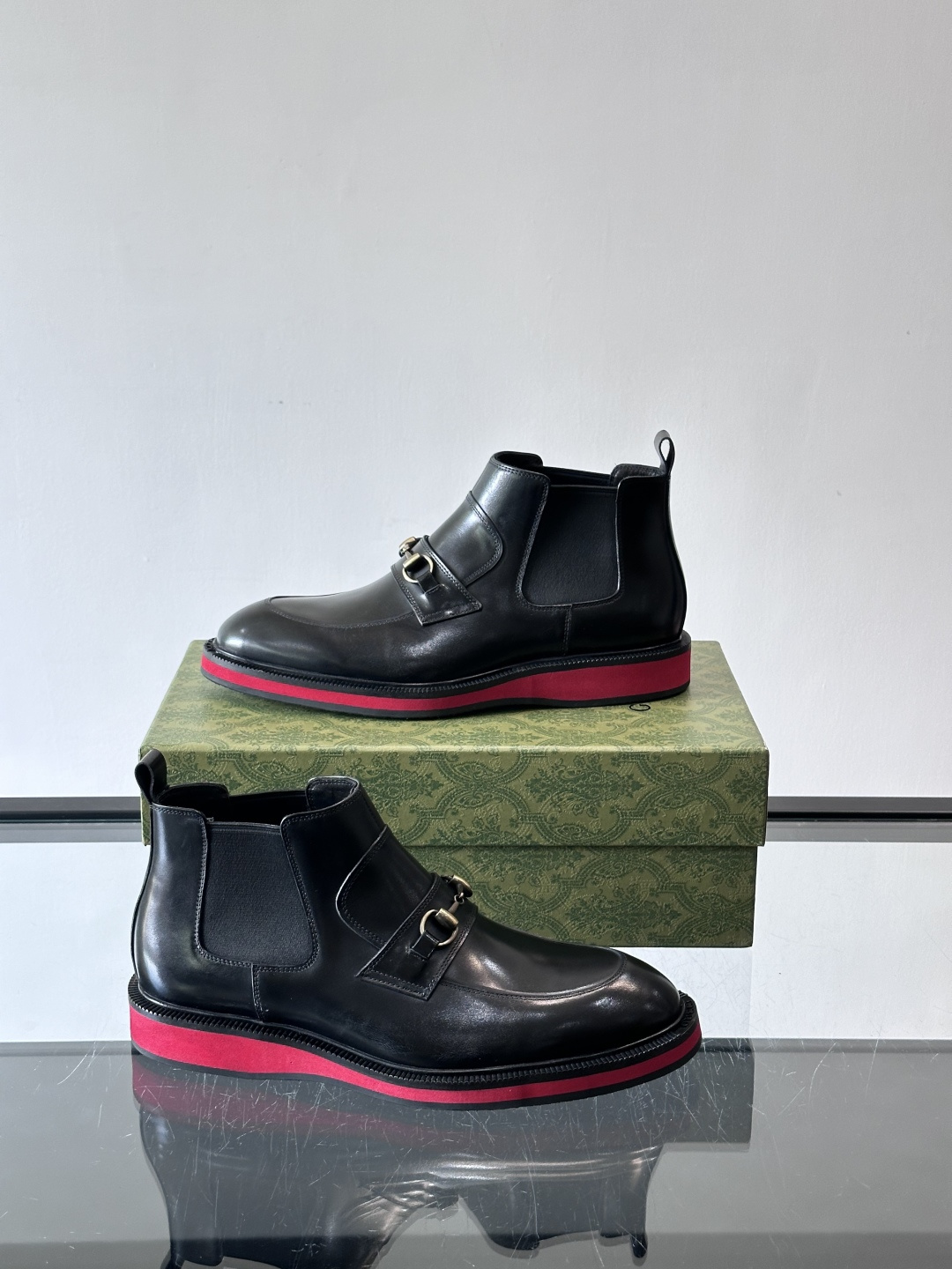 Gucci经典的拼色切尔西靴，采用高光泽黑色皮革搭配标志性的红绿织带细节，鞋底为亮眼的红色，整体设计兼具