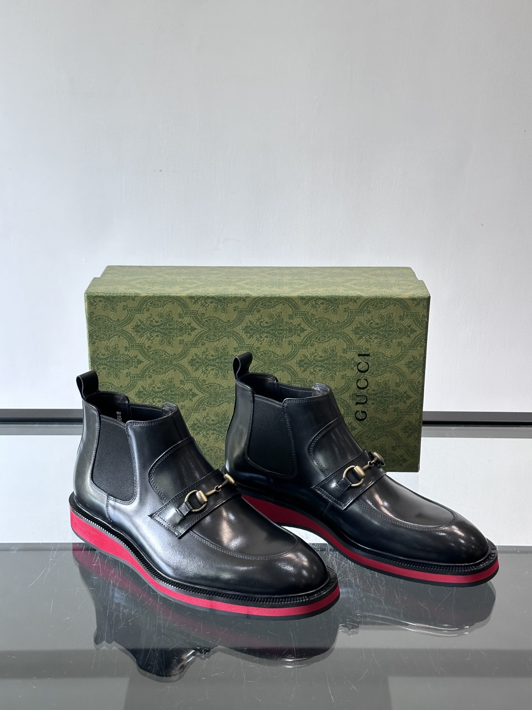 Gucci经典的拼色切尔西靴，采用高光泽黑色皮革搭配标志性的红绿织带细节，鞋底为亮眼的红色，整体设计兼具