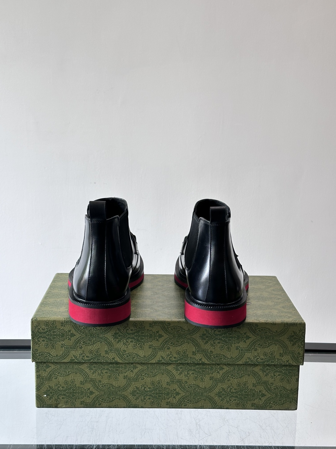 Gucci经典的拼色切尔西靴，采用高光泽黑色皮革搭配标志性的红绿织带细节，鞋底为亮眼的红色，整体设计兼具
