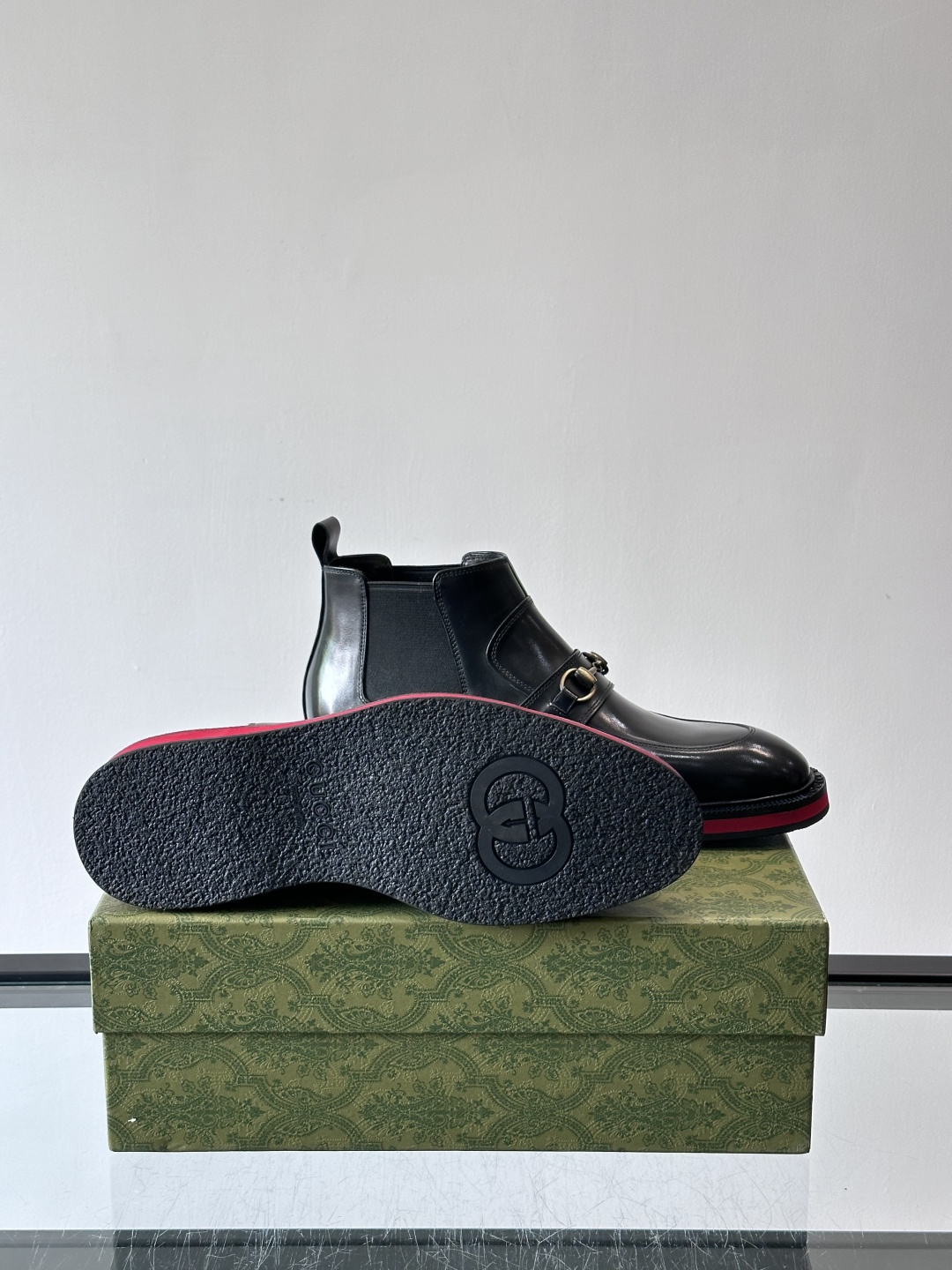 Gucci经典的拼色切尔西靴，采用高光泽黑色皮革搭配标志性的红绿织带细节，鞋底为亮眼的红色，整体设计兼具