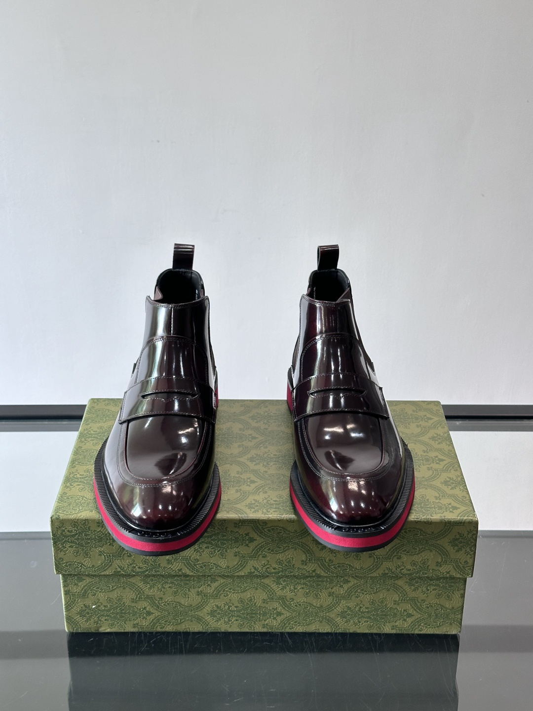 Gucci经典的拼色切尔西靴，采用高光泽黑色皮革搭配标志性的红绿织带细节，鞋底为亮眼的红色，整体设计兼具