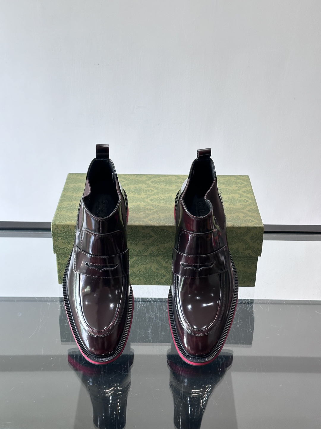 Gucci经典的拼色切尔西靴，采用高光泽黑色皮革搭配标志性的红绿织带细节，鞋底为亮眼的红色，整体设计兼具