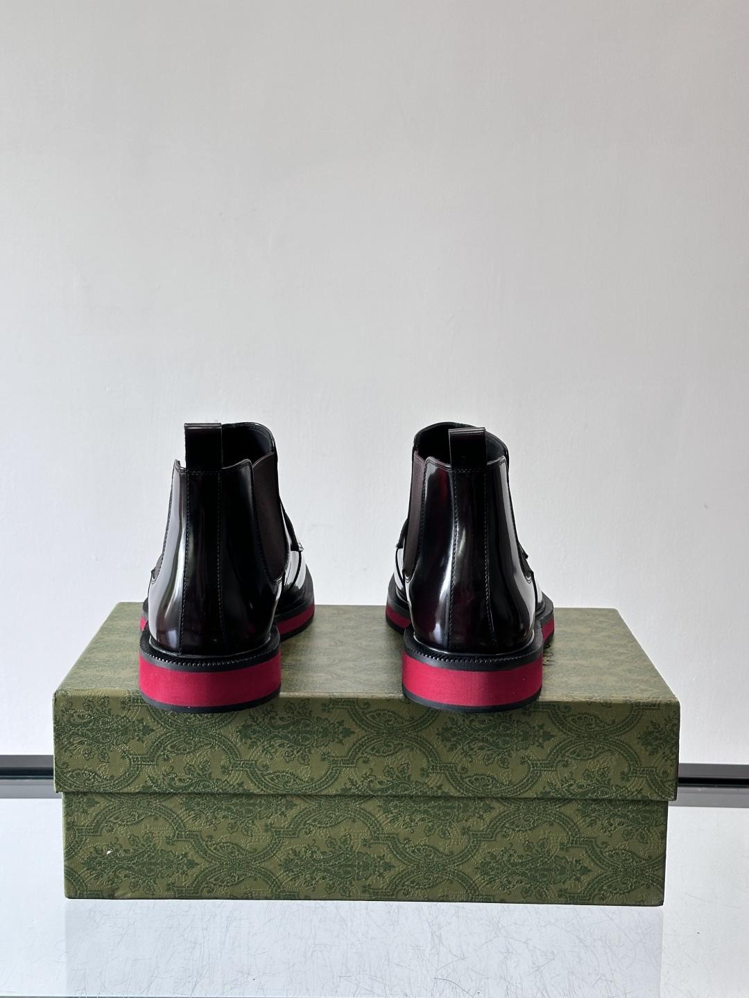 Gucci经典的拼色切尔西靴，采用高光泽黑色皮革搭配标志性的红绿织带细节，鞋底为亮眼的红色，整体设计兼具