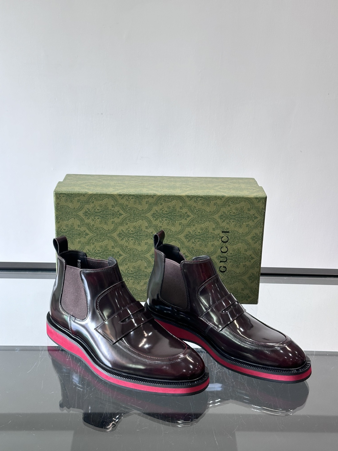 Gucci经典的拼色切尔西靴，采用高光泽黑色皮革搭配标志性的红绿织带细节，鞋底为亮眼的红色，整体设计兼具