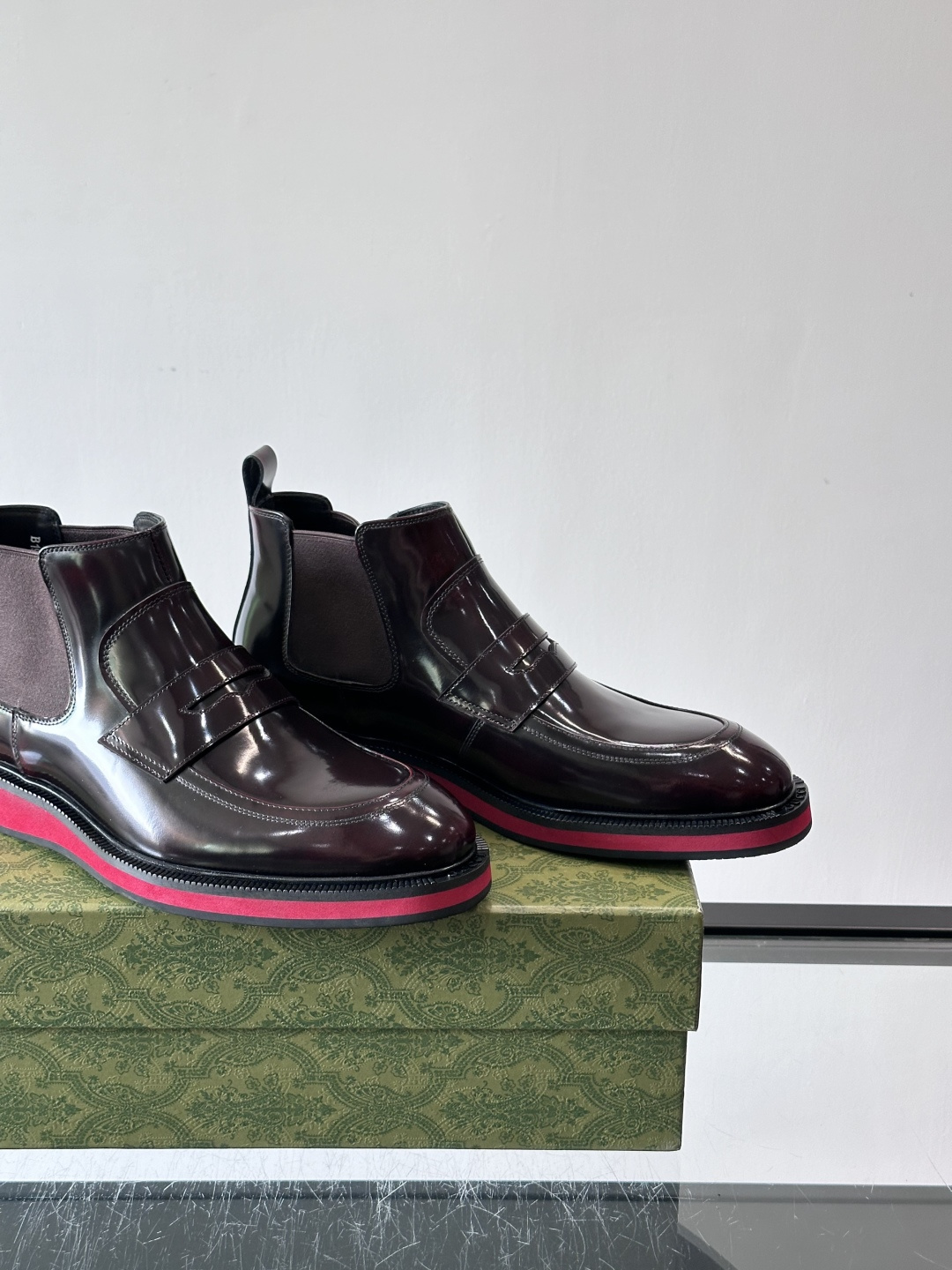 Gucci经典的拼色切尔西靴，采用高光泽黑色皮革搭配标志性的红绿织带细节，鞋底为亮眼的红色，整体设计兼具