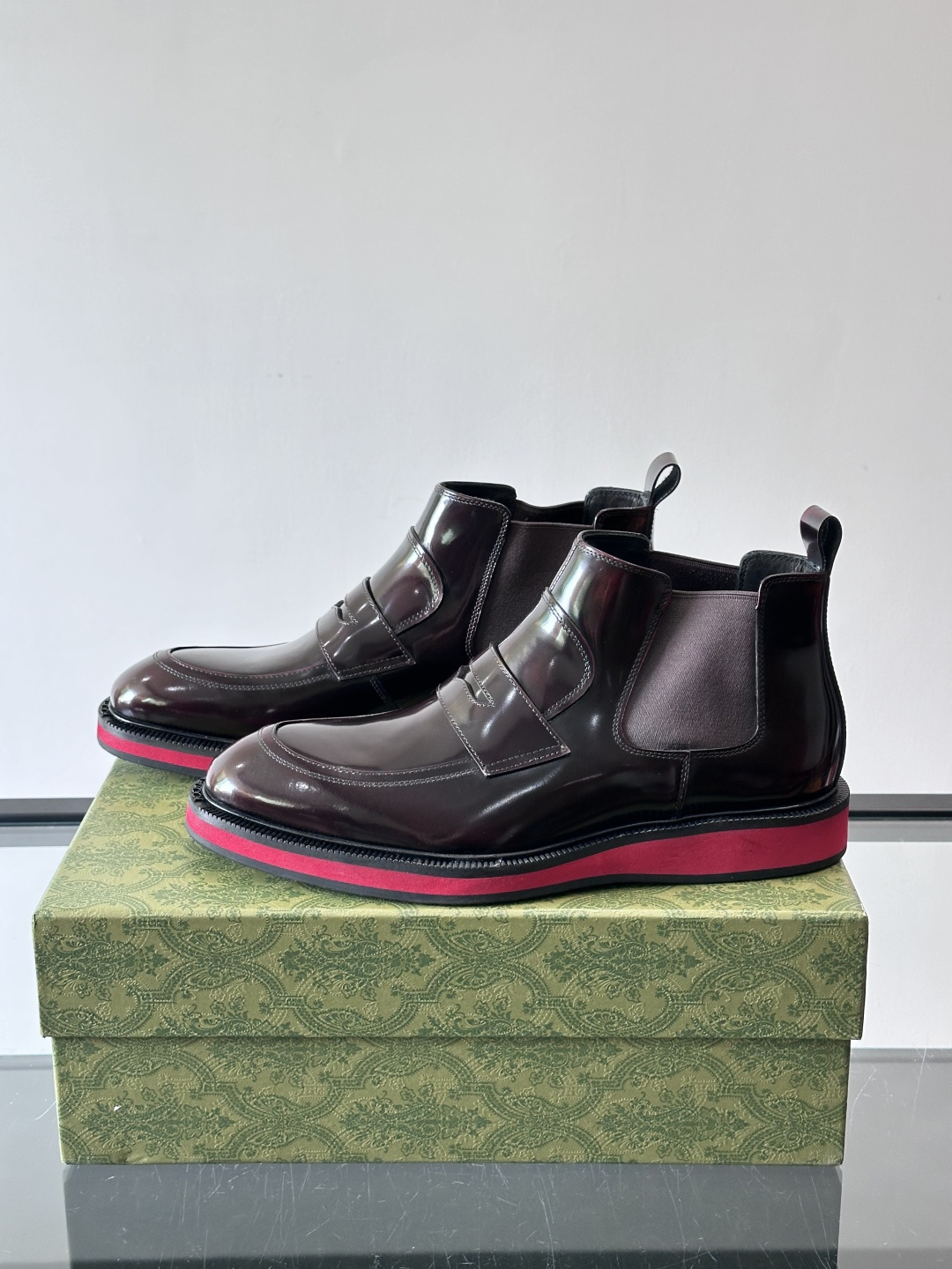 Gucci经典的拼色切尔西靴，采用高光泽黑色皮革搭配标志性的红绿织带细节，鞋底为亮眼的红色，整体设计兼具