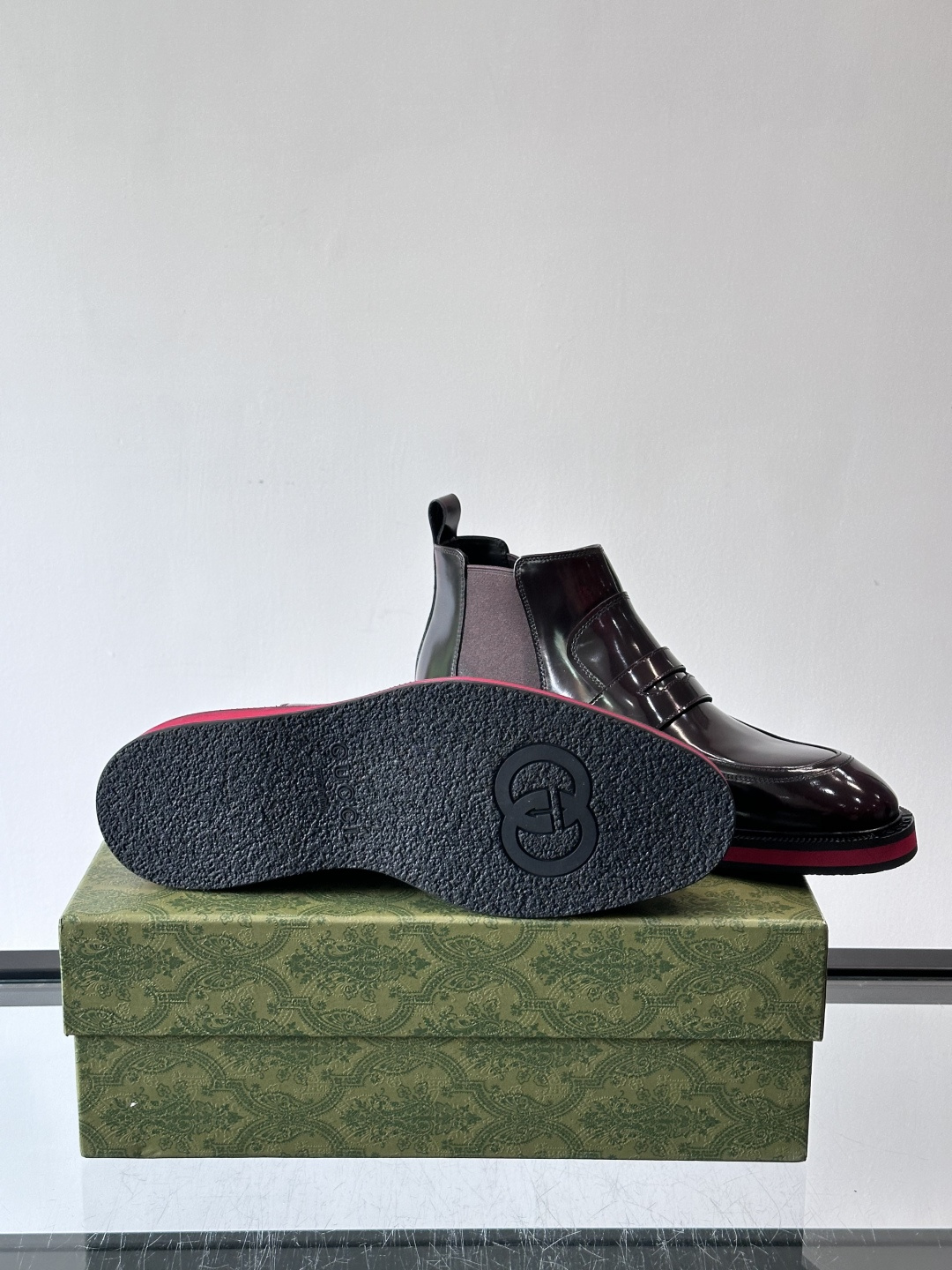 Gucci经典的拼色切尔西靴，采用高光泽黑色皮革搭配标志性的红绿织带细节，鞋底为亮眼的红色，整体设计兼具