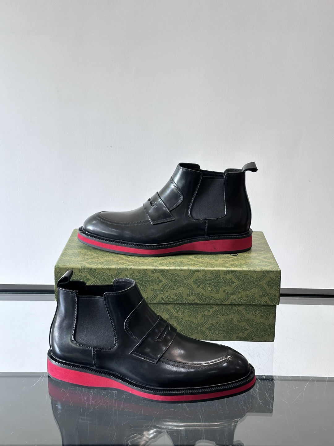 Gucci经典的拼色切尔西靴，采用高光泽黑色皮革搭配标志性的红绿织带细节，鞋底为亮眼的红色，整体设计兼具