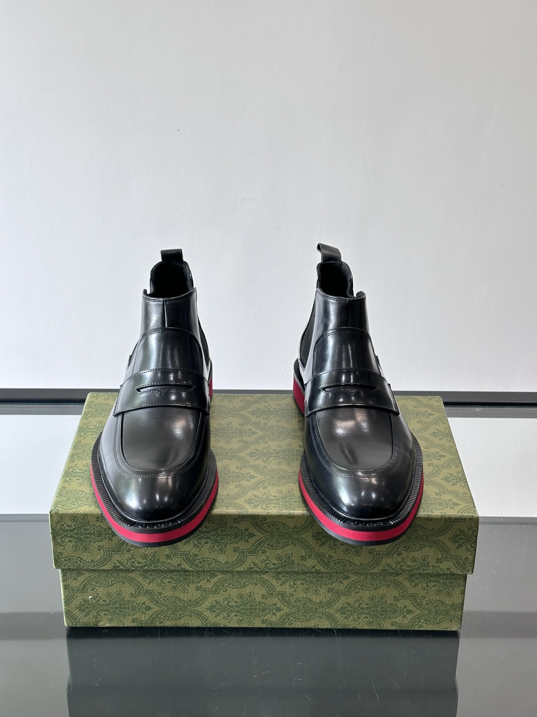 Gucci经典的拼色切尔西靴，采用高光泽黑色皮革搭配标志性的红绿织带细节，鞋底为亮眼的红色，整体设计兼具