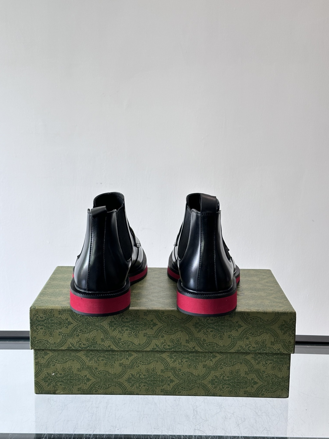 Gucci经典的拼色切尔西靴，采用高光泽黑色皮革搭配标志性的红绿织带细节，鞋底为亮眼的红色，整体设计兼具