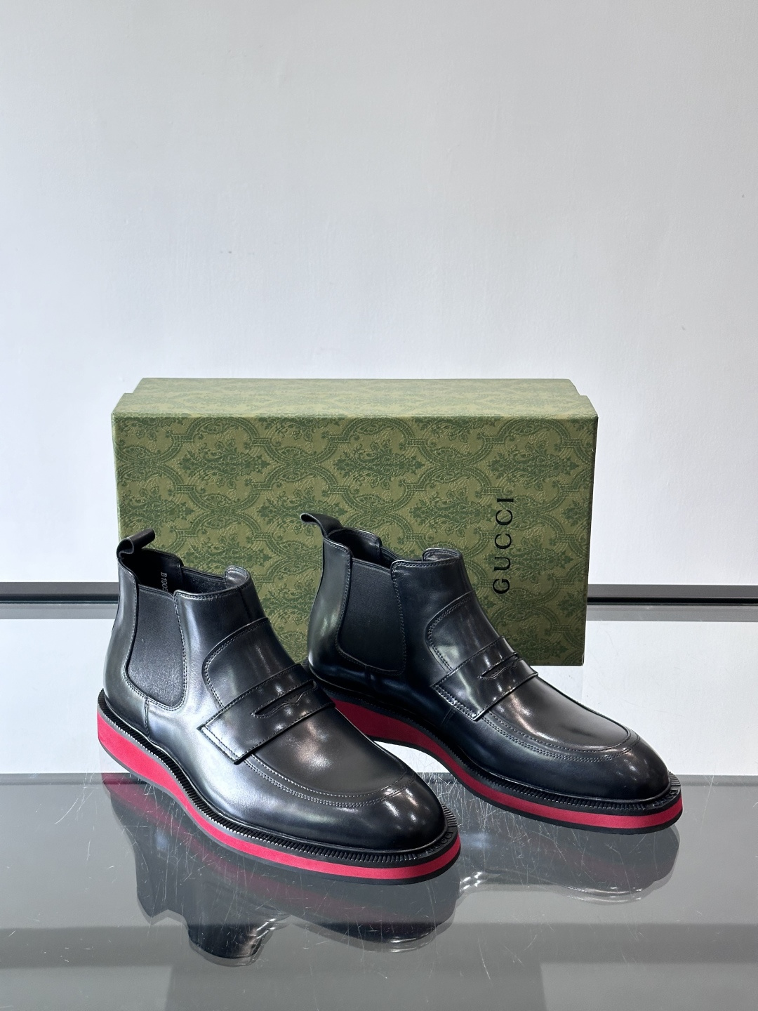 Gucci经典的拼色切尔西靴，采用高光泽黑色皮革搭配标志性的红绿织带细节，鞋底为亮眼的红色，整体设计兼具