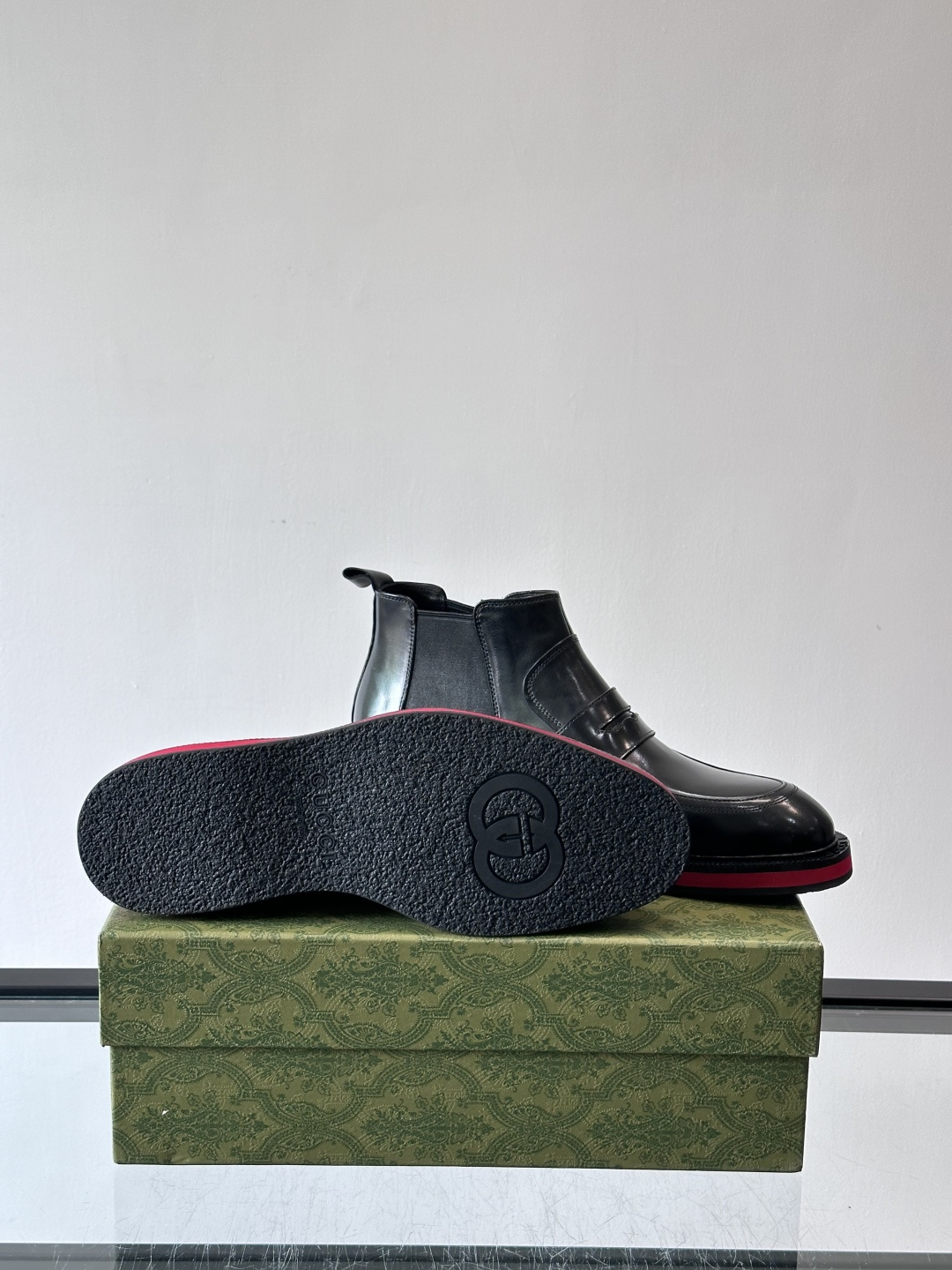 Gucci经典的拼色切尔西靴，采用高光泽黑色皮革搭配标志性的红绿织带细节，鞋底为亮眼的红色，整体设计兼具