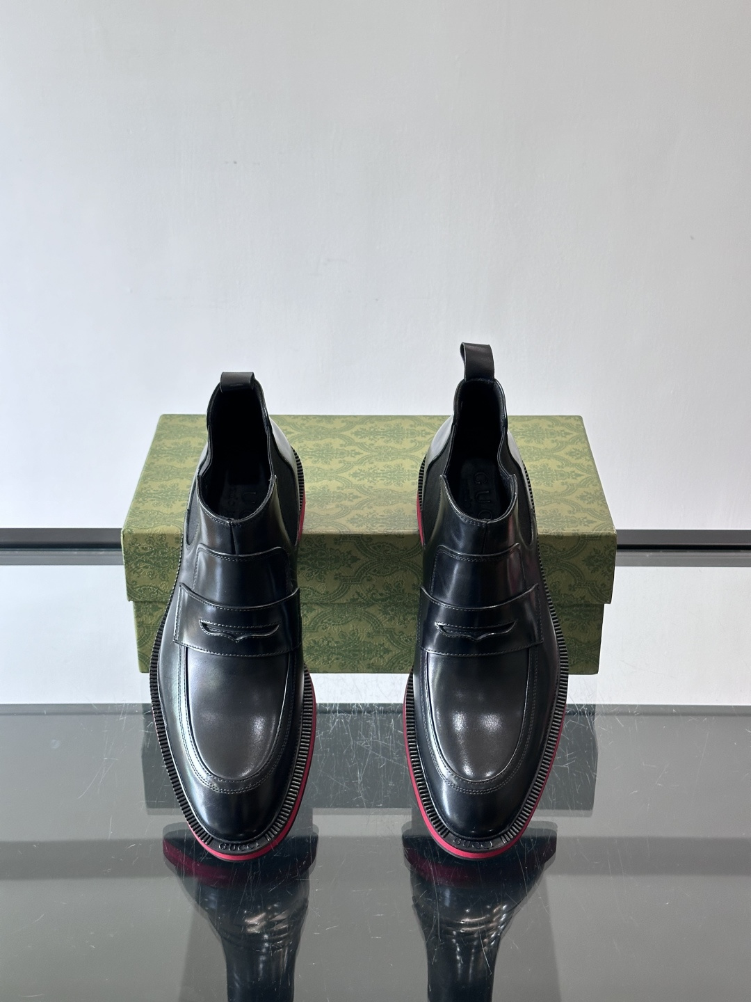 Gucci经典的拼色切尔西靴，采用高光泽黑色皮革搭配标志性的红绿织带细节，鞋底为亮眼的红色，整体设计兼具