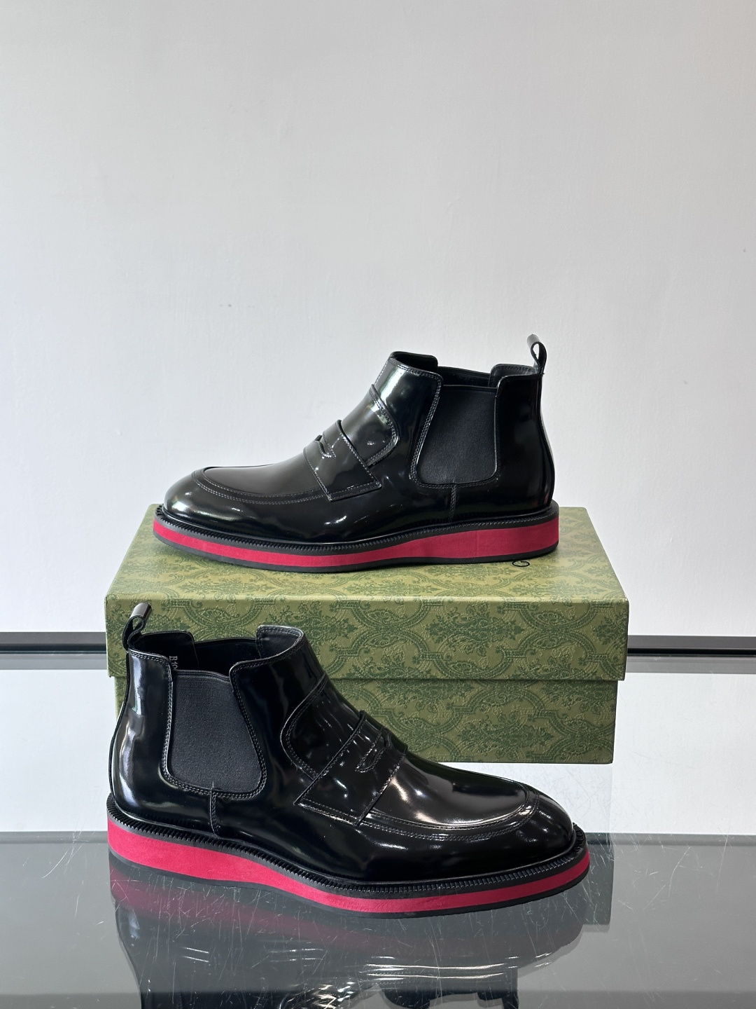 Gucci经典的拼色切尔西靴，采用高光泽黑色皮革搭配标志性的红绿织带细节，鞋底为亮眼的红色，整体设计兼具