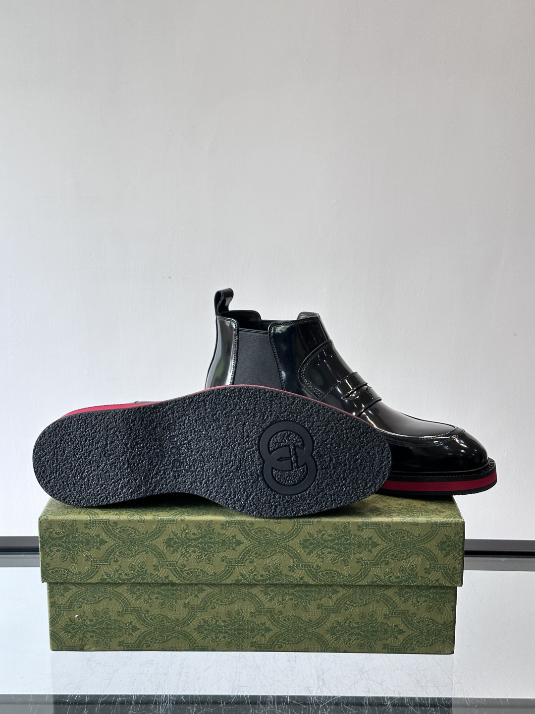 Gucci经典的拼色切尔西靴，采用高光泽黑色皮革搭配标志性的红绿织带细节，鞋底为亮眼的红色，整体设计兼具