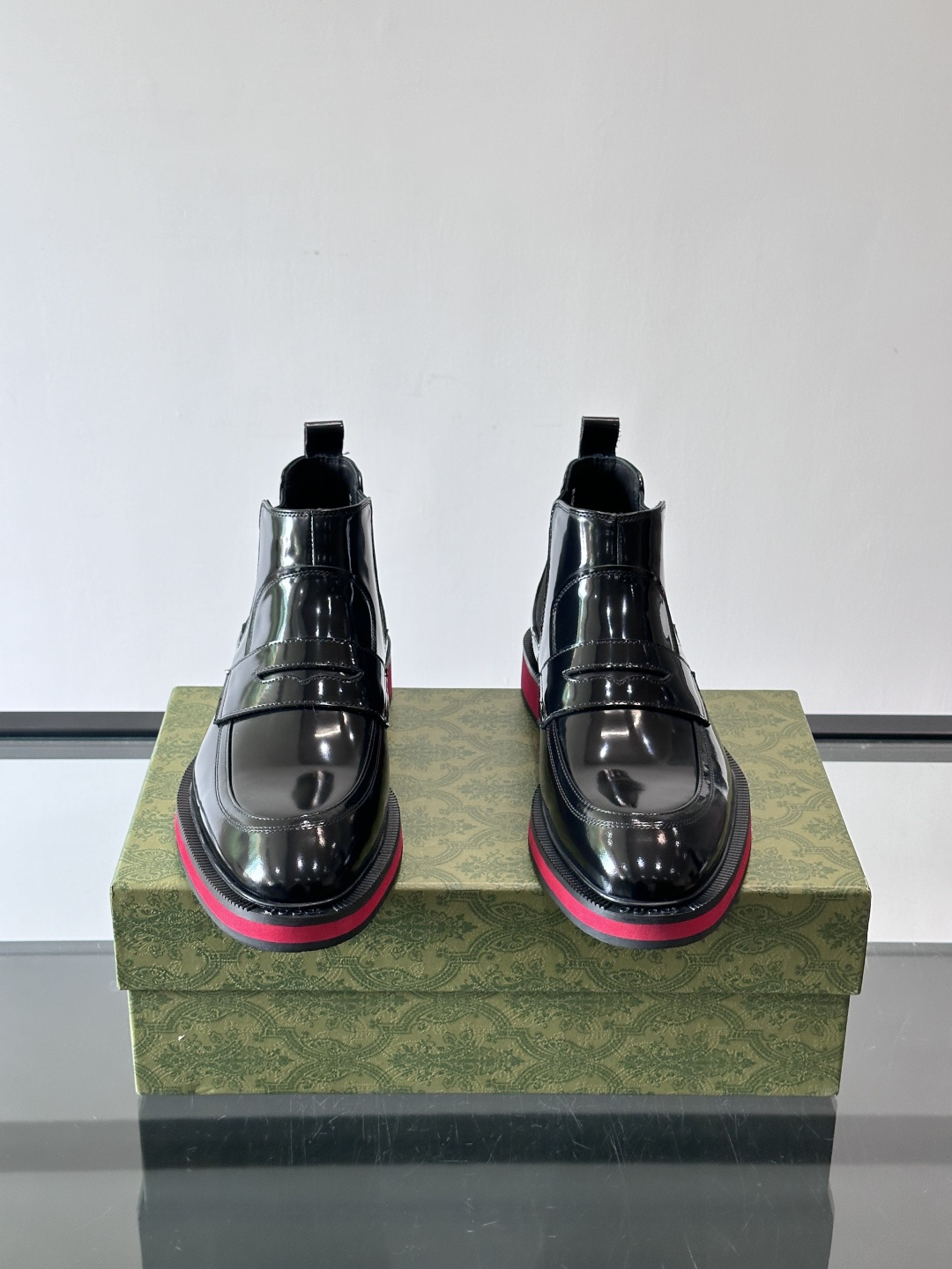 Gucci经典的拼色切尔西靴，采用高光泽黑色皮革搭配标志性的红绿织带细节，鞋底为亮眼的红色，整体设计兼具