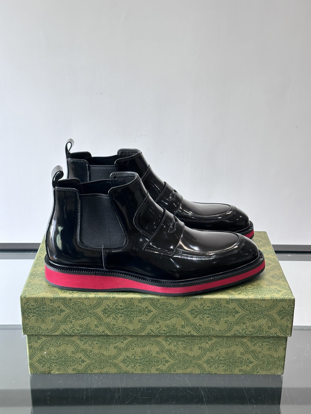 Gucci经典的拼色切尔西靴，采用高光泽黑色皮革搭配标志性的红绿织带细节，鞋底为亮眼的红色，整体设计兼具