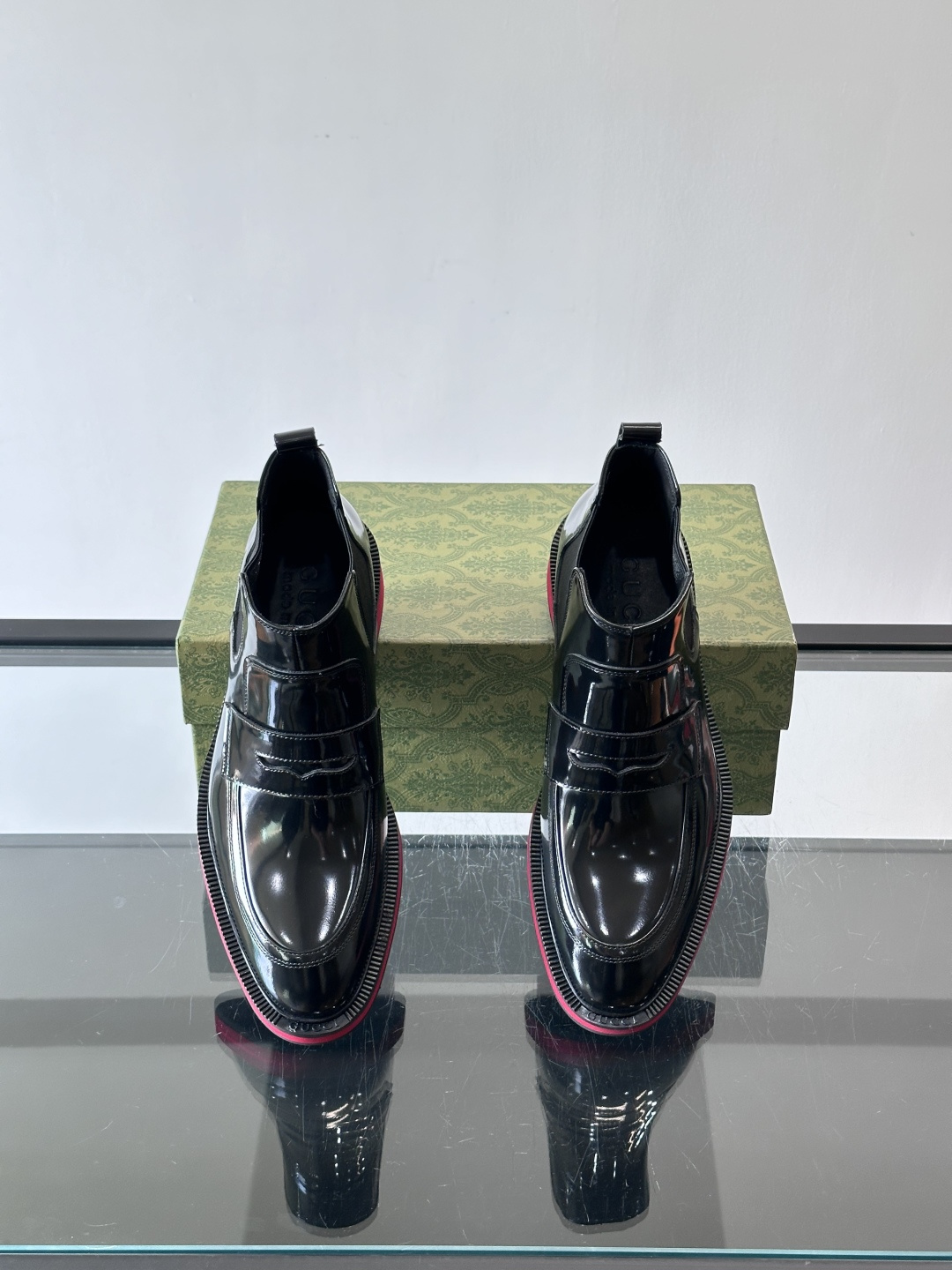 Gucci经典的拼色切尔西靴，采用高光泽黑色皮革搭配标志性的红绿织带细节，鞋底为亮眼的红色，整体设计兼具