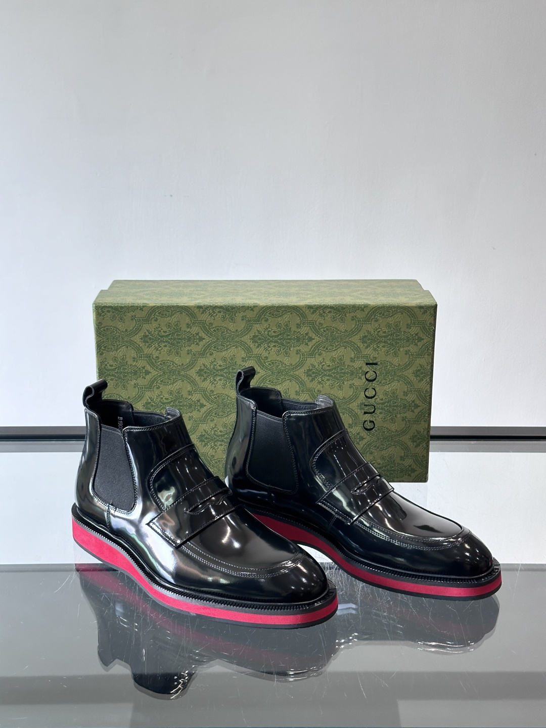 Gucci经典的拼色切尔西靴，采用高光泽黑色皮革搭配标志性的红绿织带细节，鞋底为亮眼的红色，整体设计兼具