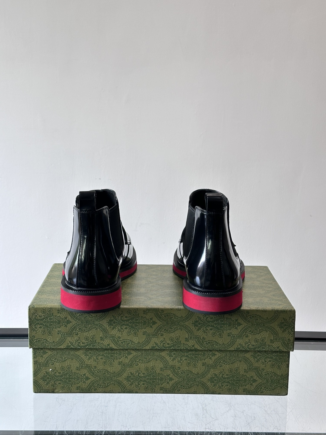 Gucci经典的拼色切尔西靴，采用高光泽黑色皮革搭配标志性的红绿织带细节，鞋底为亮眼的红色，整体设计兼具