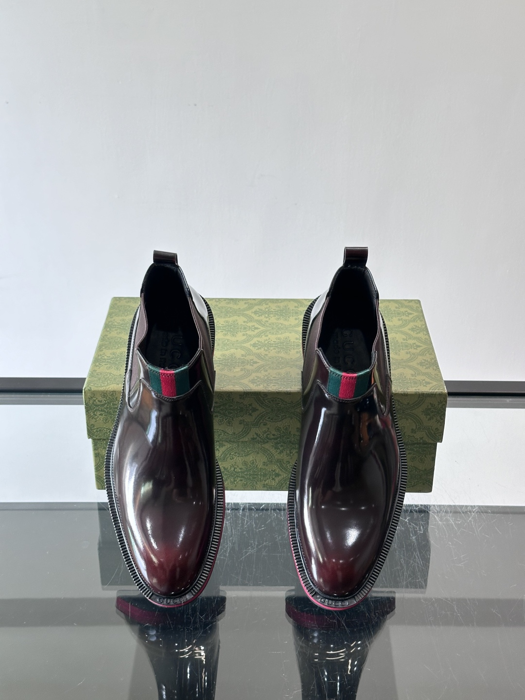 Gucci经典的拼色切尔西靴，采用高光泽黑色皮革搭配标志性的红绿织带细节，鞋底为亮眼的红色，整体设计兼具