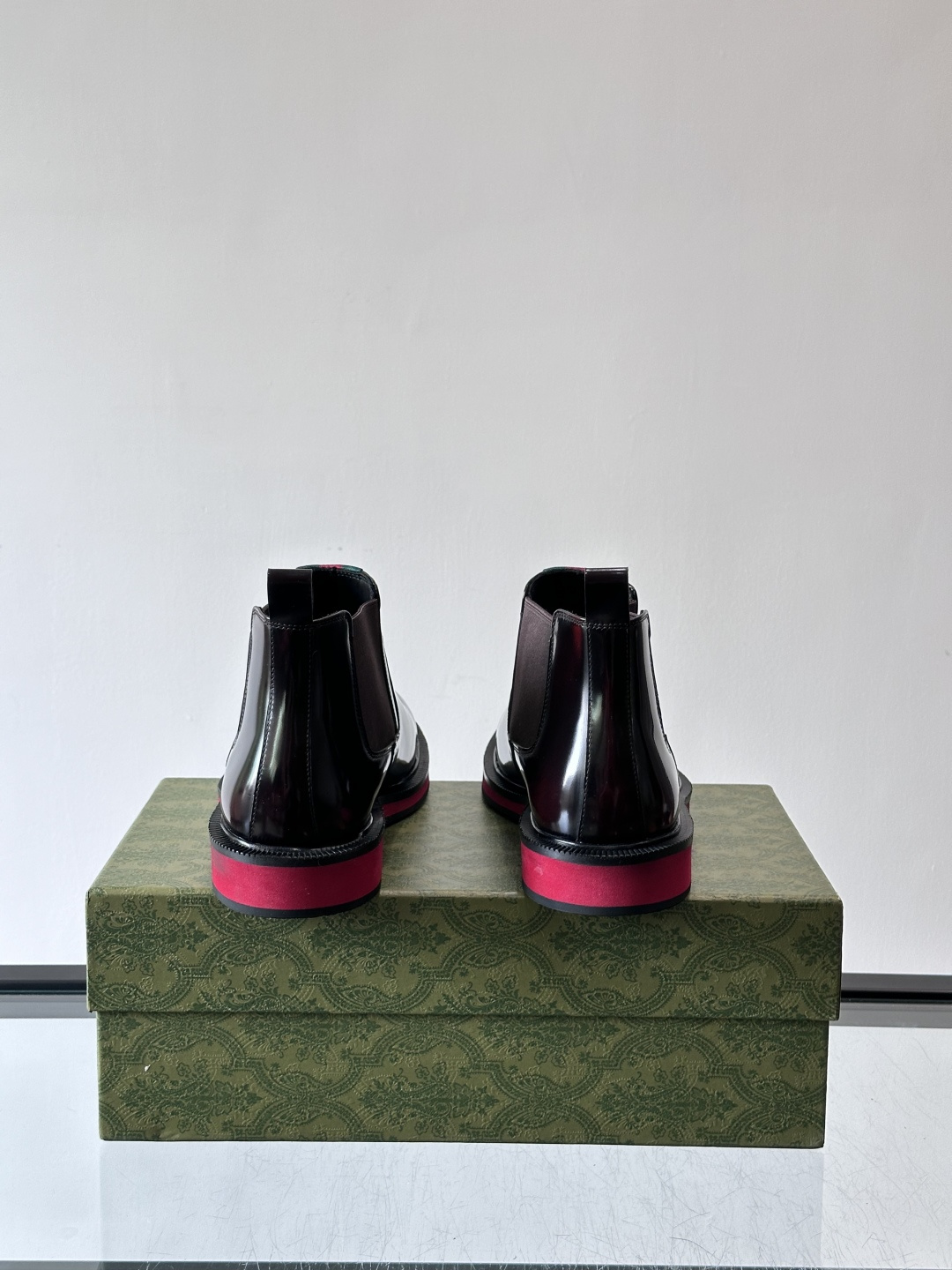 Gucci经典的拼色切尔西靴，采用高光泽黑色皮革搭配标志性的红绿织带细节，鞋底为亮眼的红色，整体设计兼具