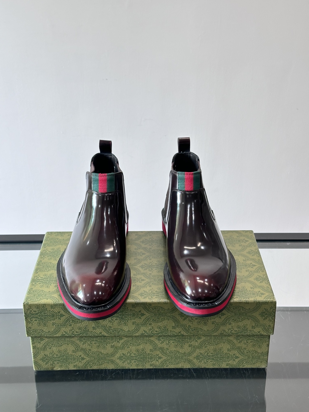 Gucci经典的拼色切尔西靴，采用高光泽黑色皮革搭配标志性的红绿织带细节，鞋底为亮眼的红色，整体设计兼具