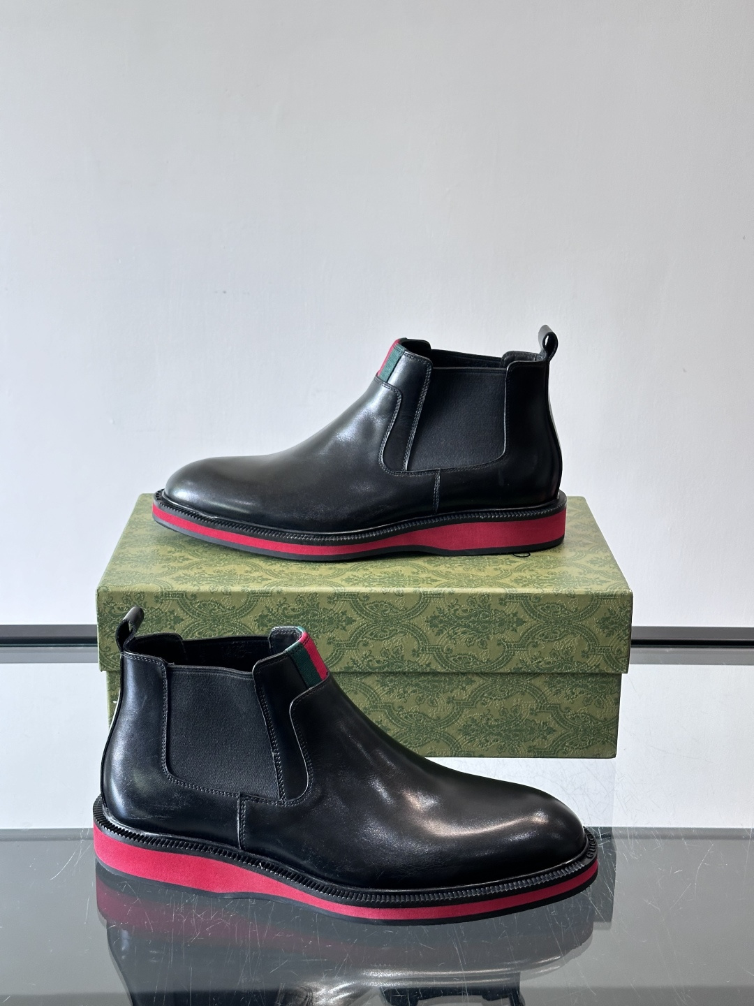 Gucci经典的拼色切尔西靴，采用高光泽黑色皮革搭配标志性的红绿织带细节，鞋底为亮眼的红色，整体设计兼具