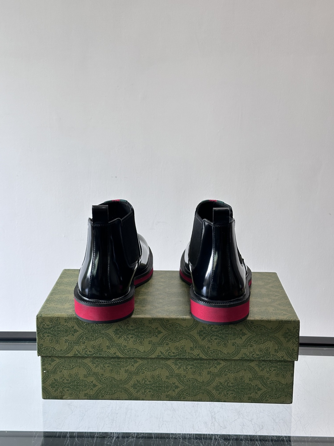 Gucci经典的拼色切尔西靴，采用高光泽黑色皮革搭配标志性的红绿织带细节，鞋底为亮眼的红色，整体设计兼具