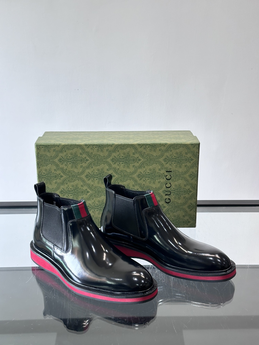 Gucci经典的拼色切尔西靴，采用高光泽黑色皮革搭配标志性的红绿织带细节，鞋底为亮眼的红色，整体设计兼具