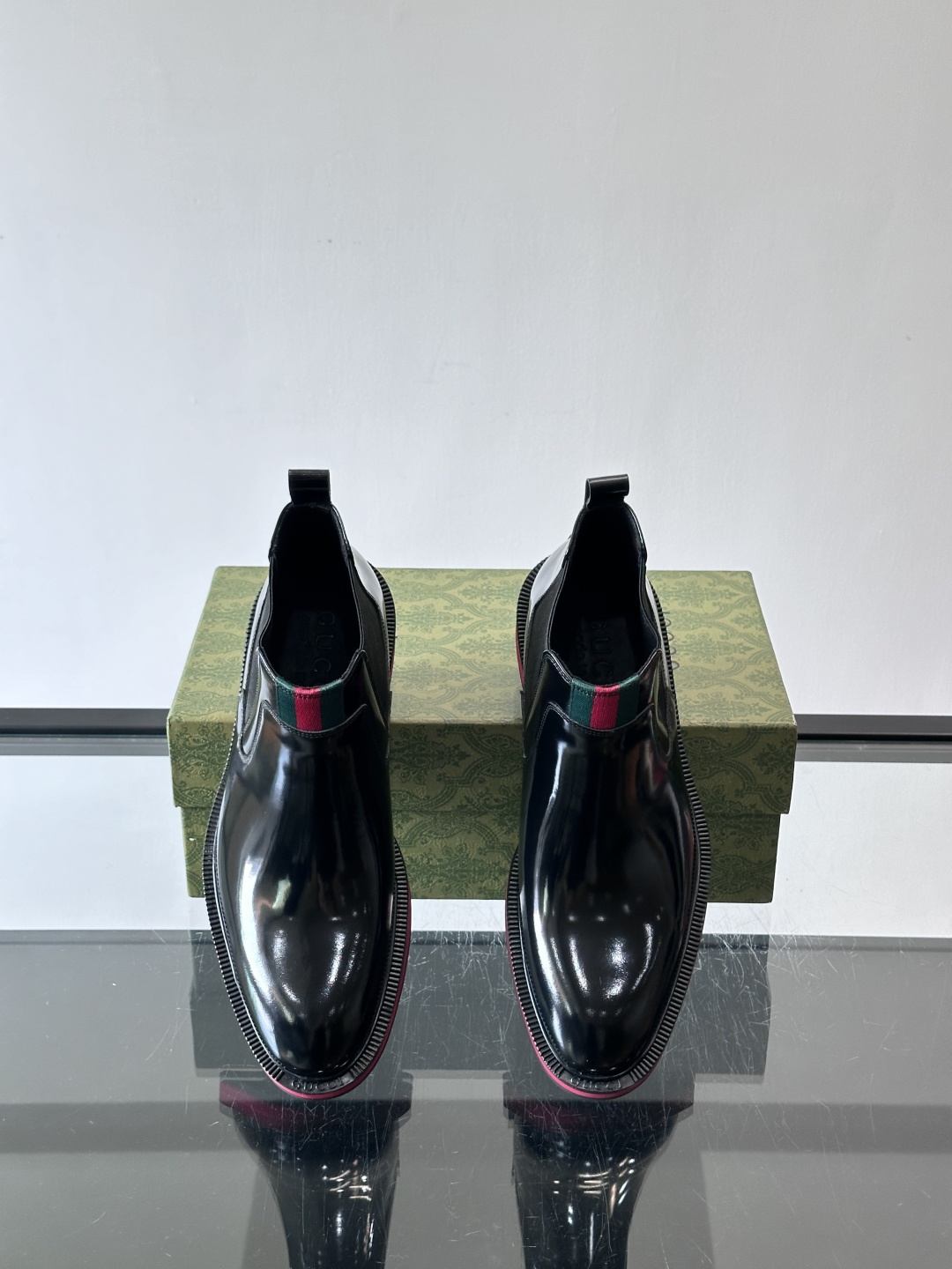 Gucci经典的拼色切尔西靴，采用高光泽黑色皮革搭配标志性的红绿织带细节，鞋底为亮眼的红色，整体设计兼具