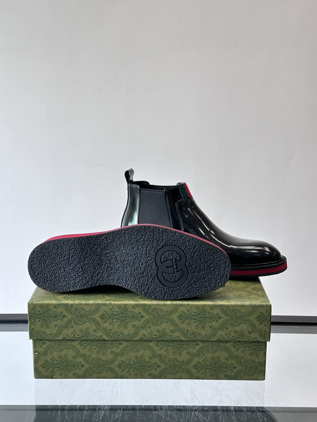 Gucci经典的拼色切尔西靴，采用高光泽黑色皮革搭配标志性的红绿织带细节，鞋底为亮眼的红色，整体设计兼具