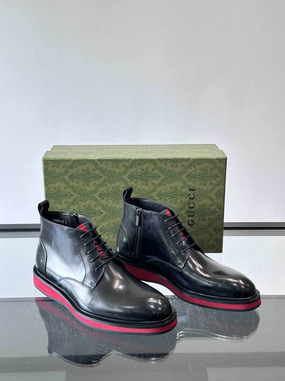 Gucci经典的拼色切尔西靴，采用高光泽黑色皮革搭配标志性的红绿织带细节，鞋底为亮眼的红色，整体设计兼具