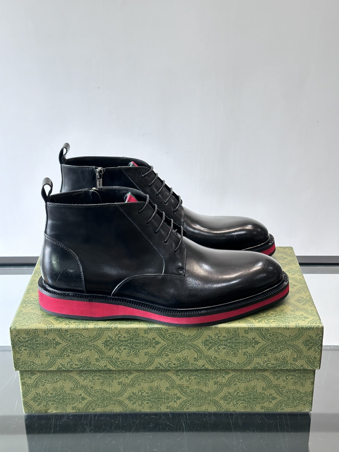 Gucci经典的拼色切尔西靴，采用高光泽黑色皮革搭配标志性的红绿织带细节，鞋底为亮眼的红色，整体设计兼具