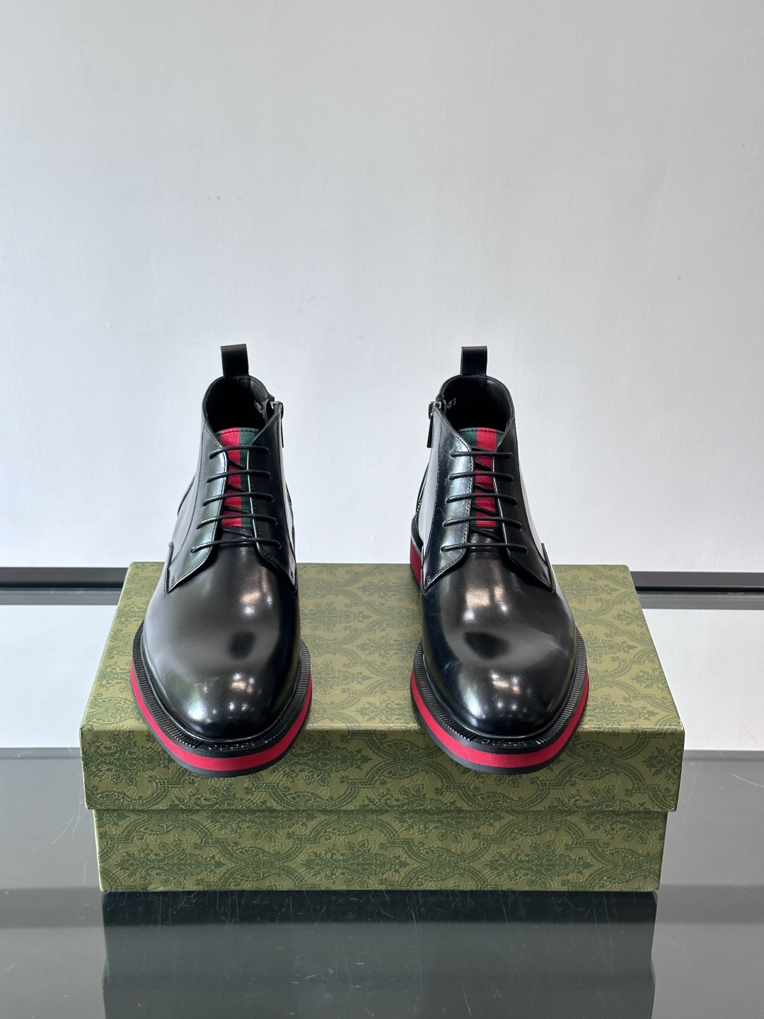 Gucci经典的拼色切尔西靴，采用高光泽黑色皮革搭配标志性的红绿织带细节，鞋底为亮眼的红色，整体设计兼具
