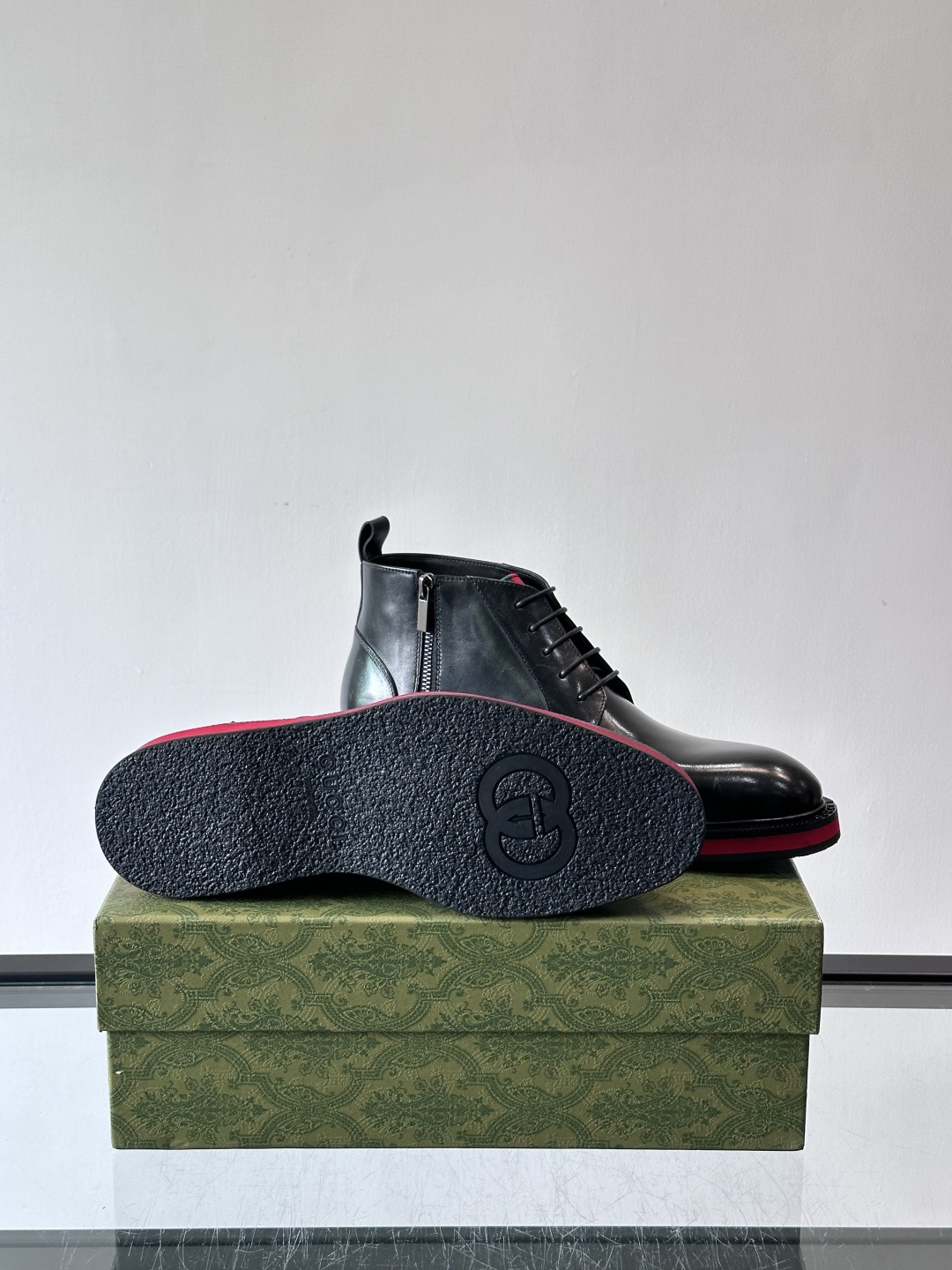 Gucci经典的拼色切尔西靴，采用高光泽黑色皮革搭配标志性的红绿织带细节，鞋底为亮眼的红色，整体设计兼具