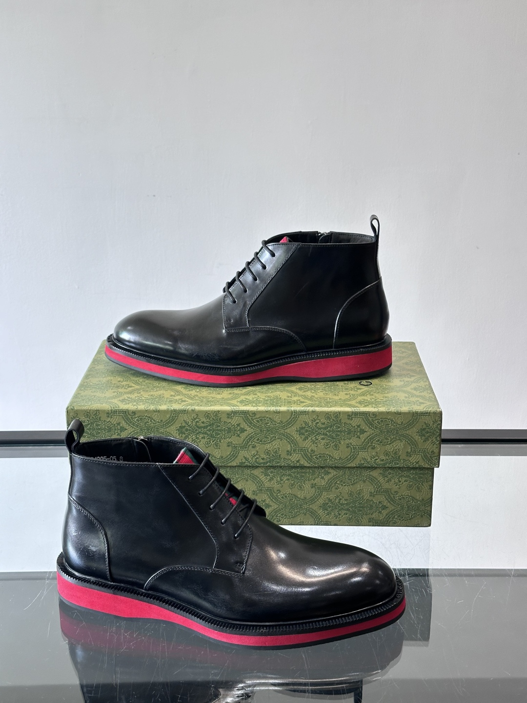 Gucci经典的拼色切尔西靴，采用高光泽黑色皮革搭配标志性的红绿织带细节，鞋底为亮眼的红色，整体设计兼具