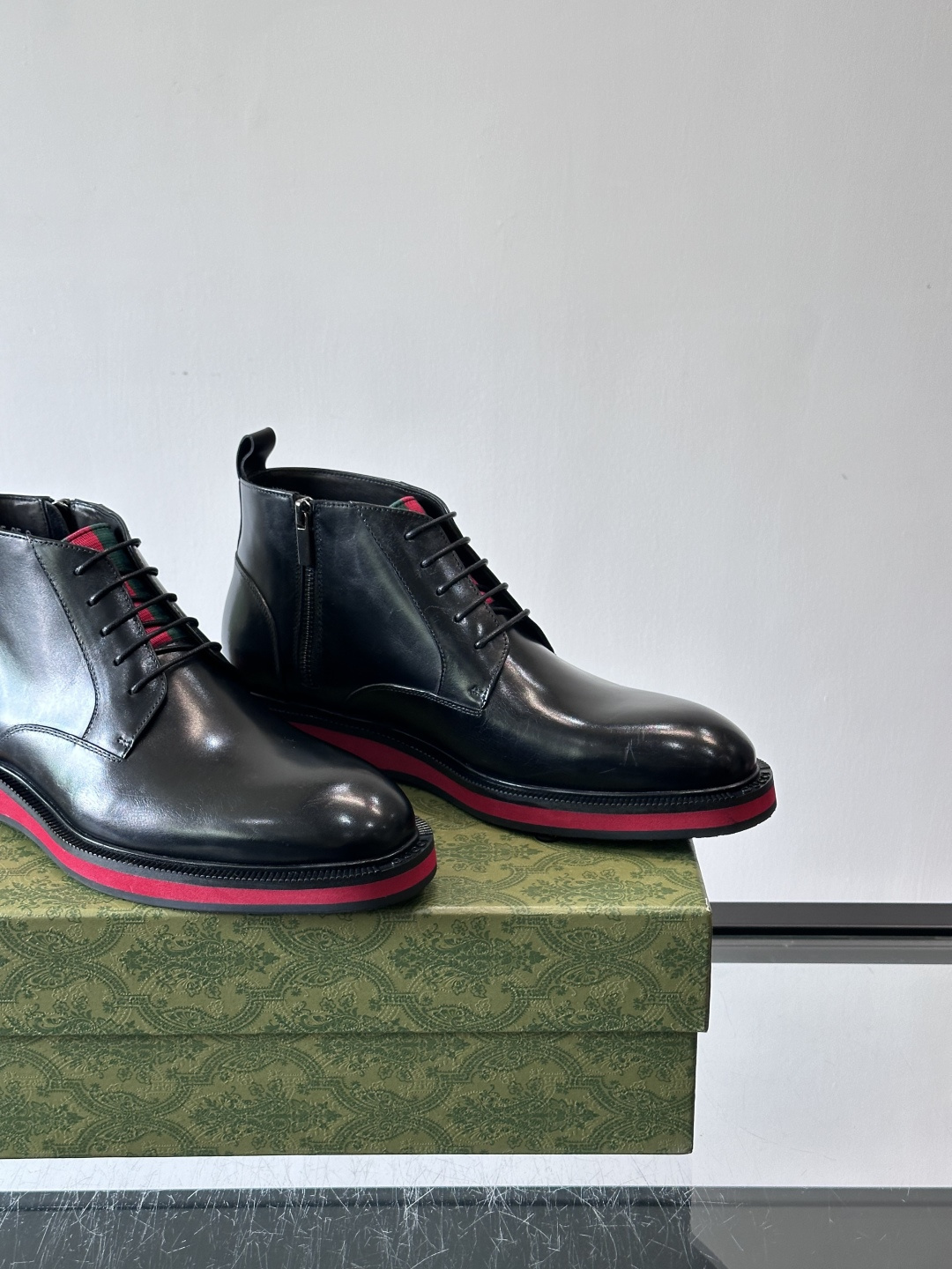 Gucci经典的拼色切尔西靴，采用高光泽黑色皮革搭配标志性的红绿织带细节，鞋底为亮眼的红色，整体设计兼具