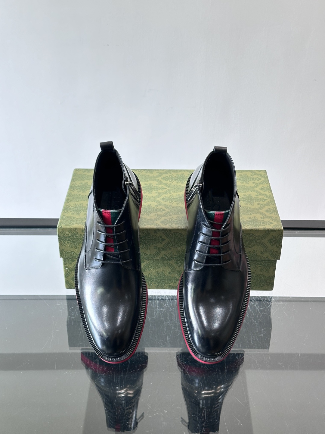 Gucci经典的拼色切尔西靴，采用高光泽黑色皮革搭配标志性的红绿织带细节，鞋底为亮眼的红色，整体设计兼具