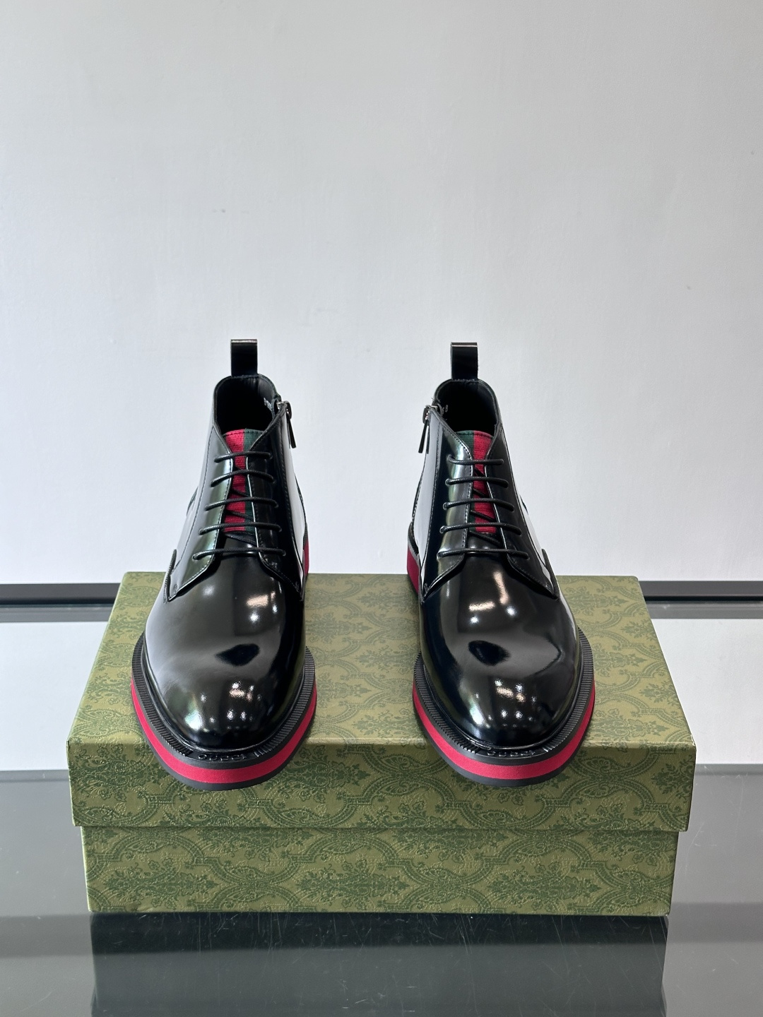 Gucci经典的拼色切尔西靴，采用高光泽黑色皮革搭配标志性的红绿织带细节，鞋底为亮眼的红色，整体设计兼具