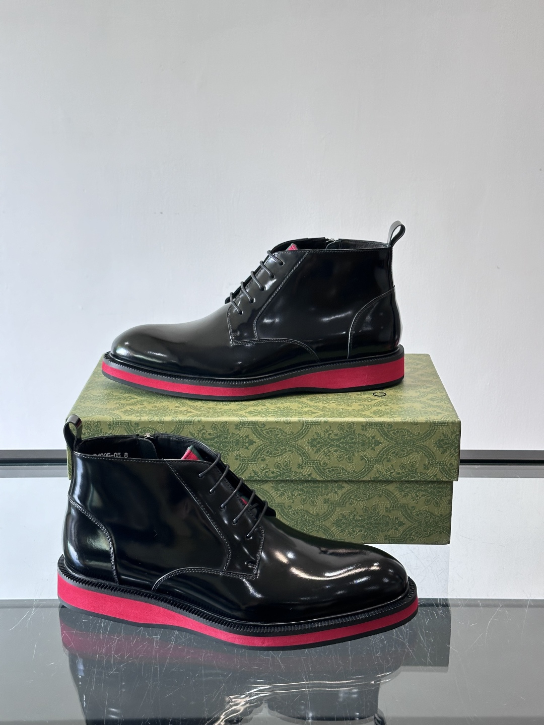 Gucci经典的拼色切尔西靴，采用高光泽黑色皮革搭配标志性的红绿织带细节，鞋底为亮眼的红色，整体设计兼具