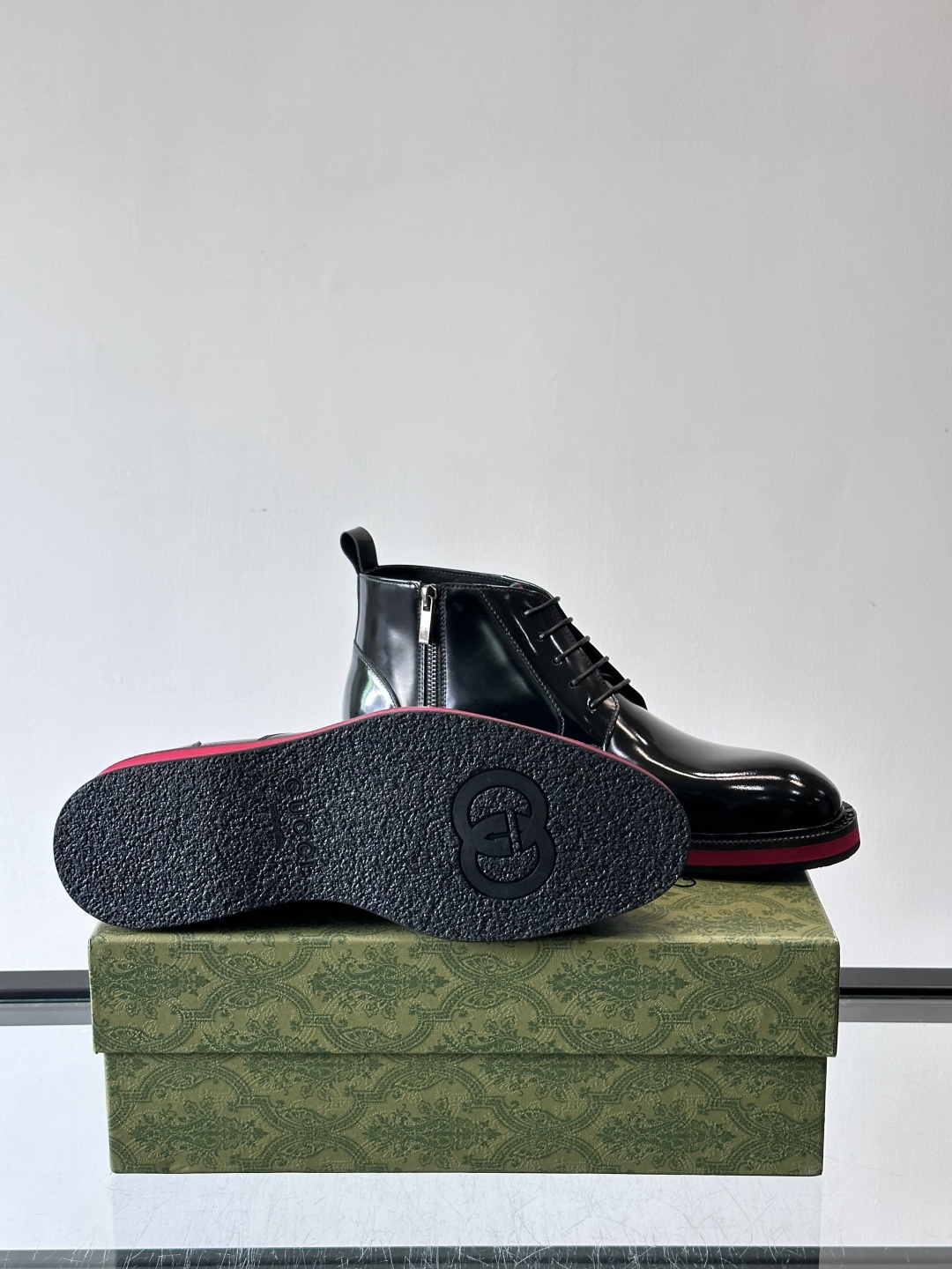 Gucci经典的拼色切尔西靴，采用高光泽黑色皮革搭配标志性的红绿织带细节，鞋底为亮眼的红色，整体设计兼具