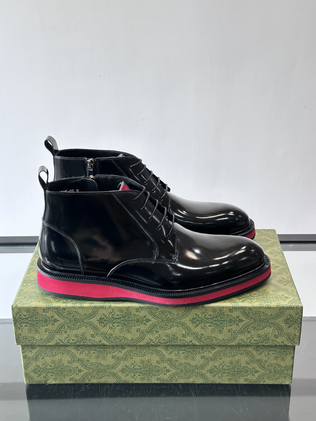 Gucci经典的拼色切尔西靴，采用高光泽黑色皮革搭配标志性的红绿织带细节，鞋底为亮眼的红色，整体设计兼具