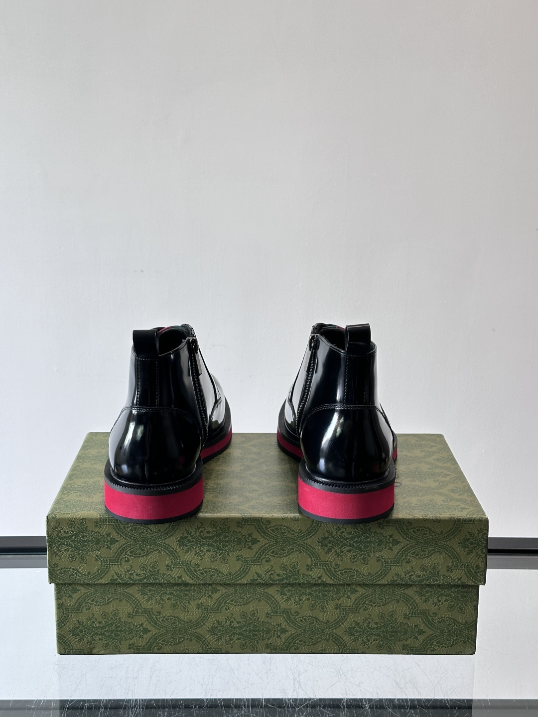 Gucci经典的拼色切尔西靴，采用高光泽黑色皮革搭配标志性的红绿织带细节，鞋底为亮眼的红色，整体设计兼具