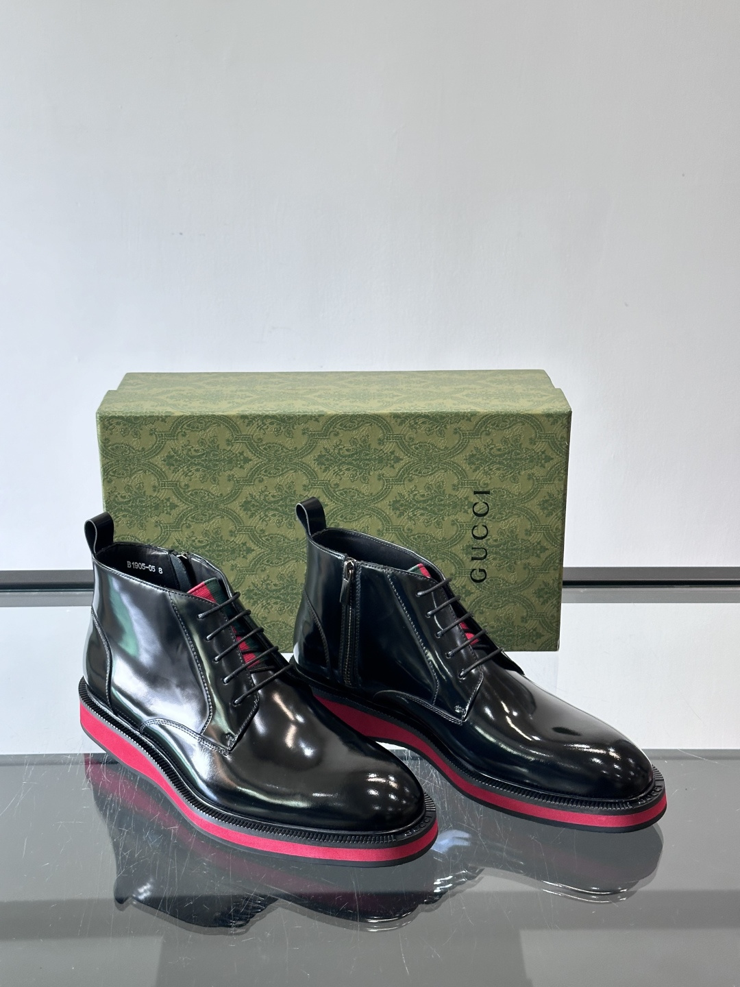 Gucci经典的拼色切尔西靴，采用高光泽黑色皮革搭配标志性的红绿织带细节，鞋底为亮眼的红色，整体设计兼具