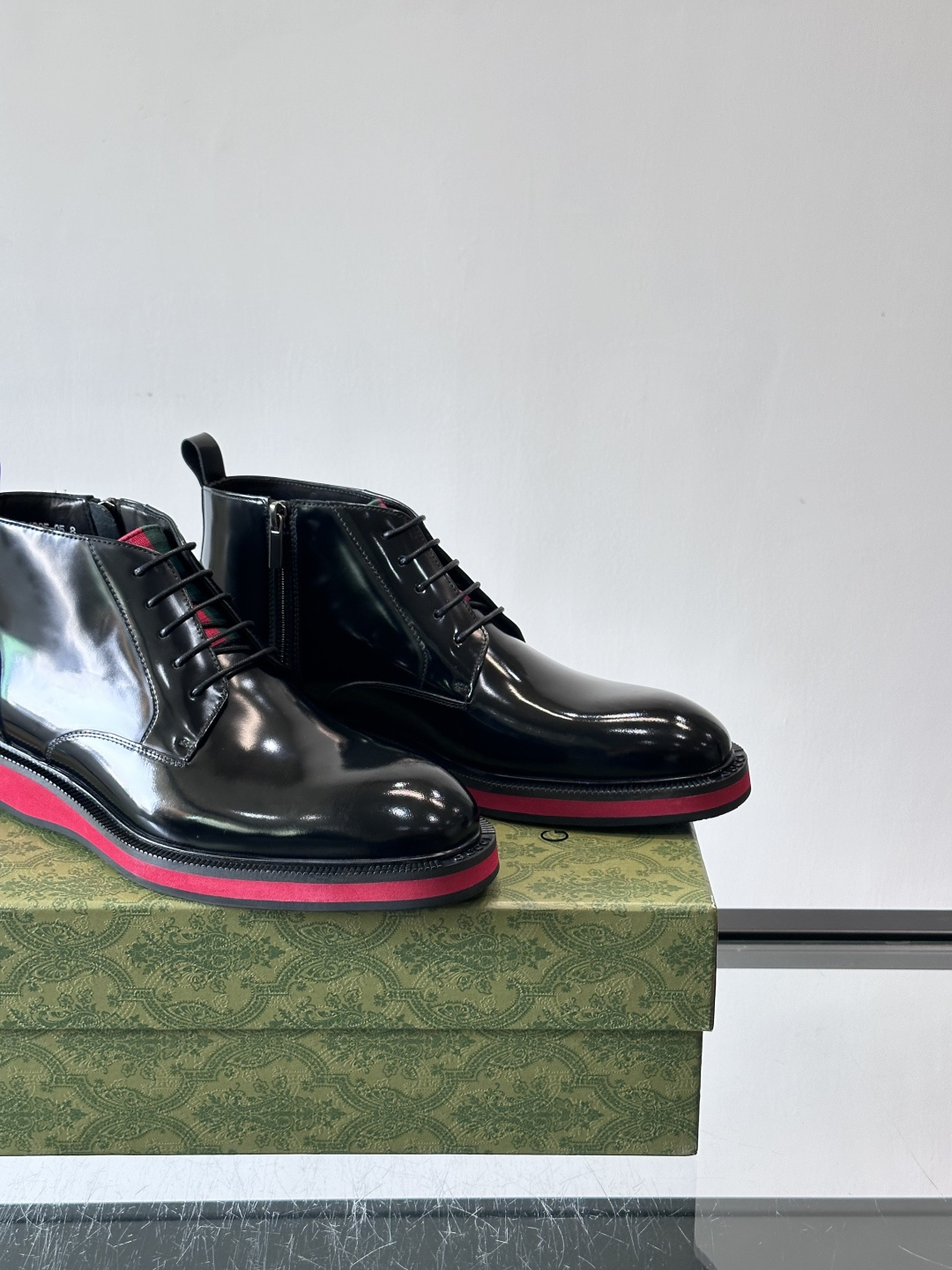 Gucci经典的拼色切尔西靴，采用高光泽黑色皮革搭配标志性的红绿织带细节，鞋底为亮眼的红色，整体设计兼具