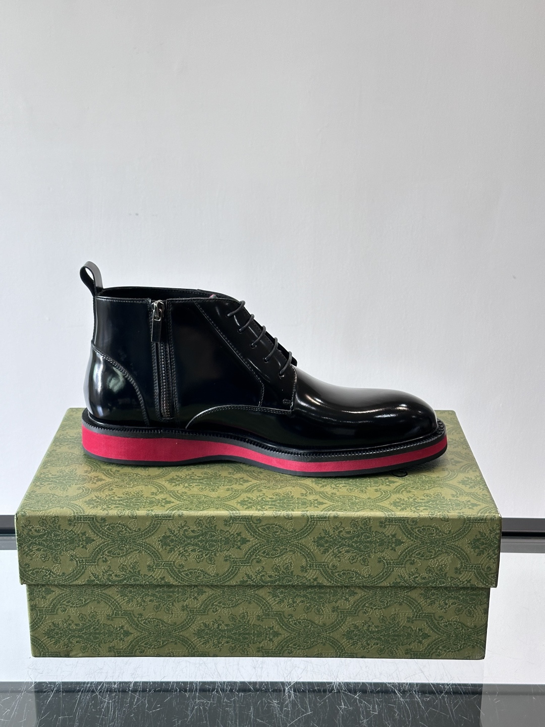 Gucci经典的拼色切尔西靴，采用高光泽黑色皮革搭配标志性的红绿织带细节，鞋底为亮眼的红色，整体设计兼具