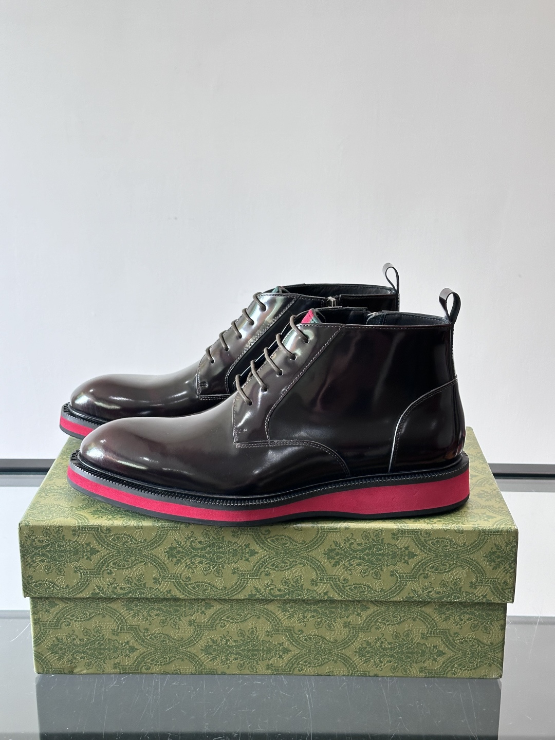 Gucci经典的拼色切尔西靴，采用高光泽黑色皮革搭配标志性的红绿织带细节，鞋底为亮眼的红色，整体设计兼具