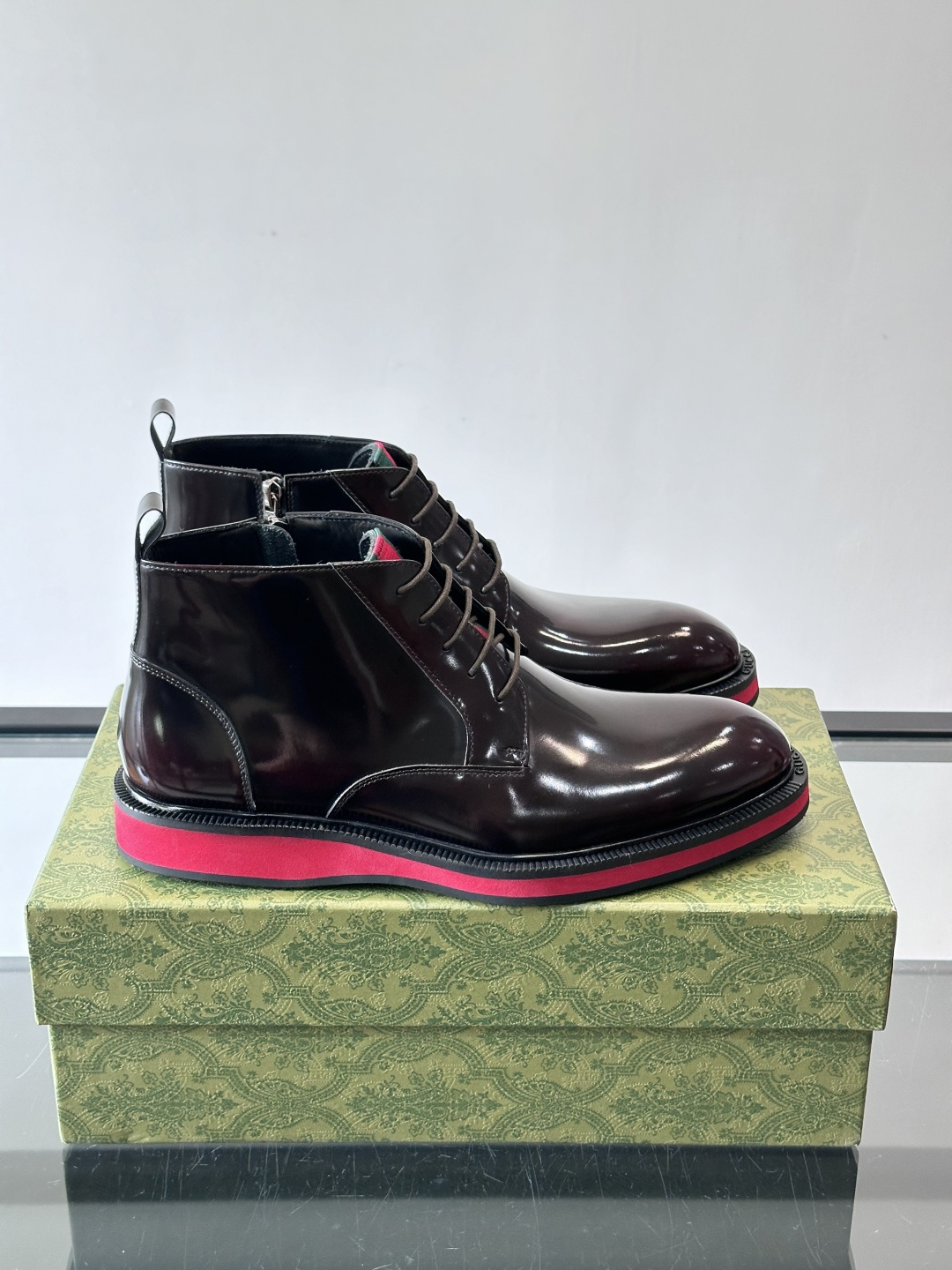 Gucci经典的拼色切尔西靴，采用高光泽黑色皮革搭配标志性的红绿织带细节，鞋底为亮眼的红色，整体设计兼具