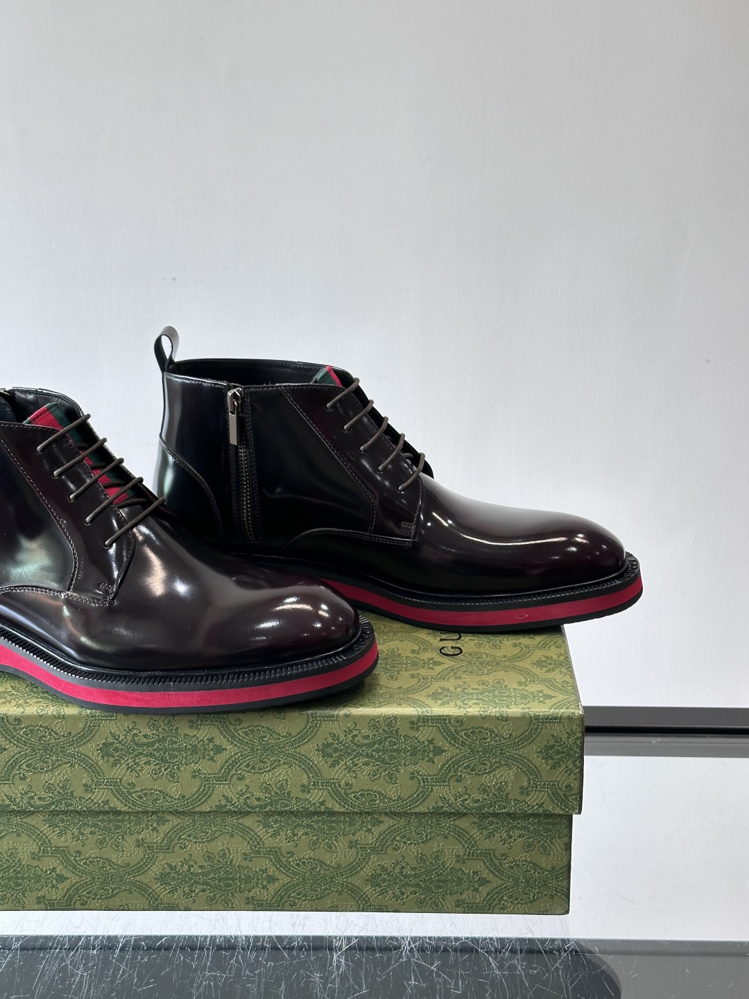 Gucci经典的拼色切尔西靴，采用高光泽黑色皮革搭配标志性的红绿织带细节，鞋底为亮眼的红色，整体设计兼具
